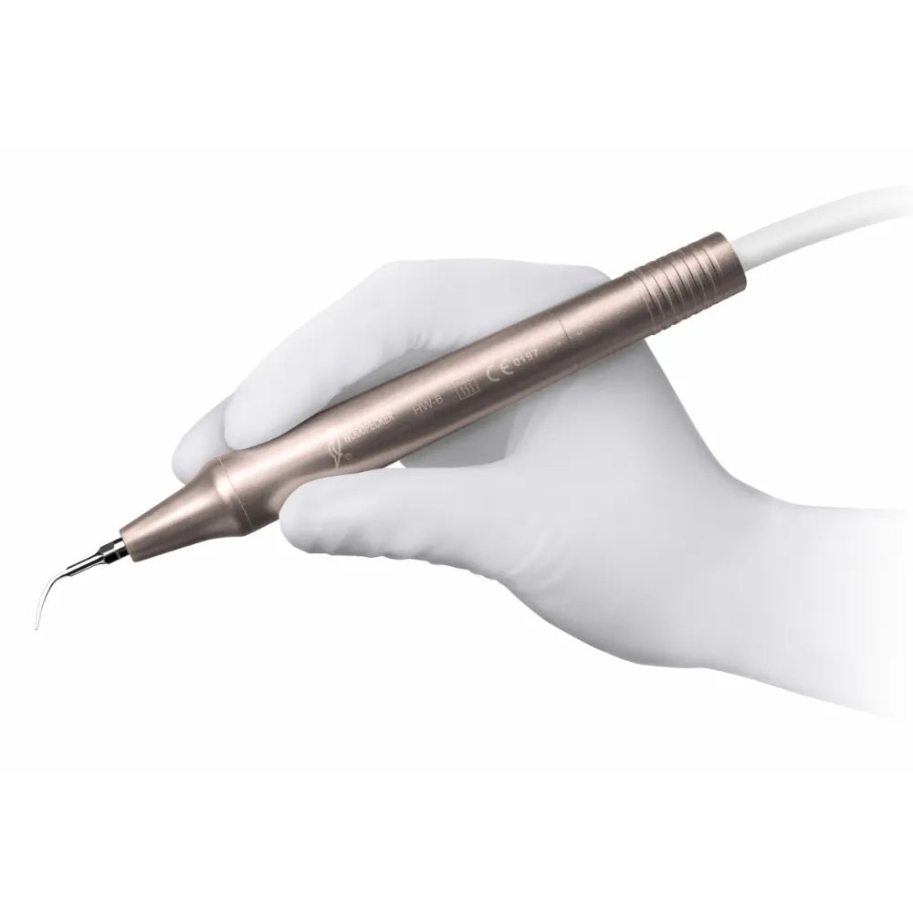 Gloved hand holding Woodpecker ultrasonic scaler handpiece in rose gold with curved periodontal tip